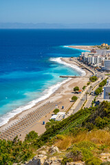 Aegean beach with sunshades in city of Rhodes (Rhodes, Greece)
