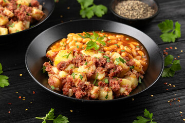 Corned beef hash with potatoes and beans in tomato sauce.