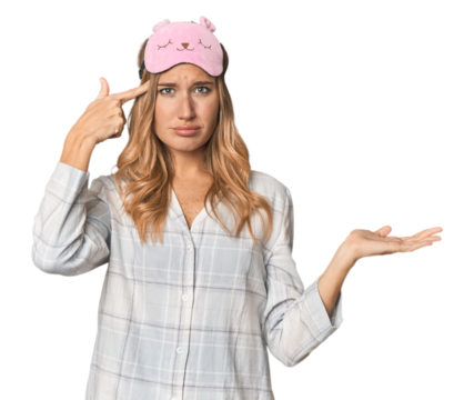 Blonde in pajamas with sleep mask holding and showing a product on hand.