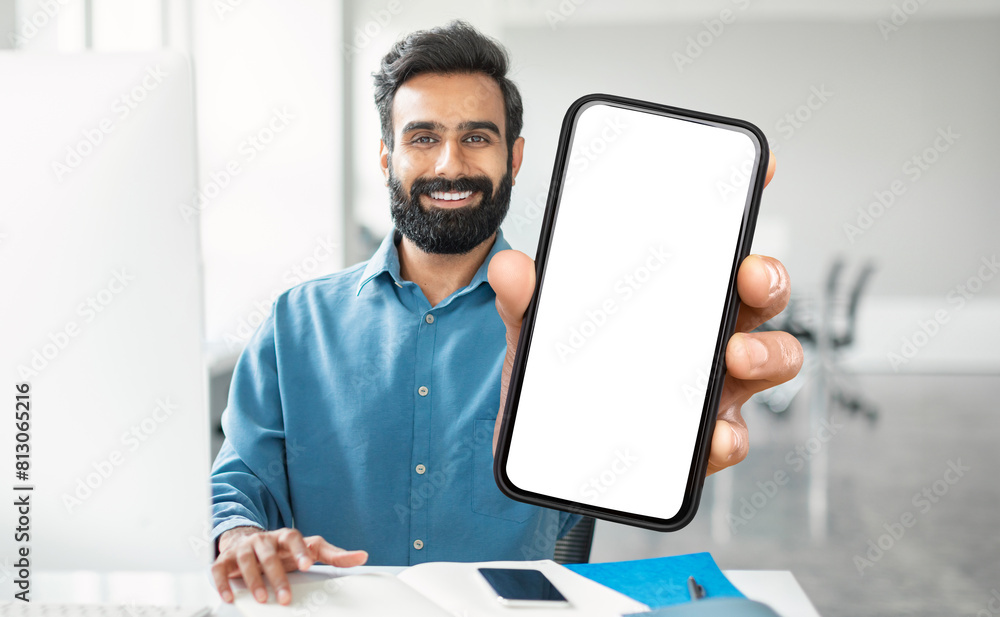 Poster Indian man is shown holding a cell phone with a blank screen in his hand. He appears to be looking at the device intently, possibly waiting for a message or call.