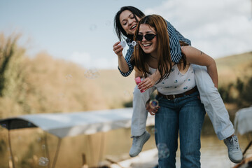 Carefree moments captured as two friends have fun outdoors, blowing bubbles and enjoying a joyous...