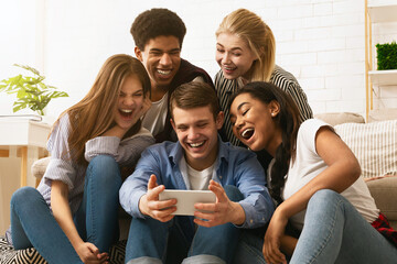 A cheerful group of multiethnic teenagers is clustered together on a couch, enjoying a moment of...