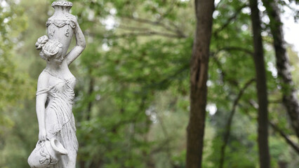 sculpture of a girl in the spring park. An old statue in a park of a semi-nude Greek or Italian...