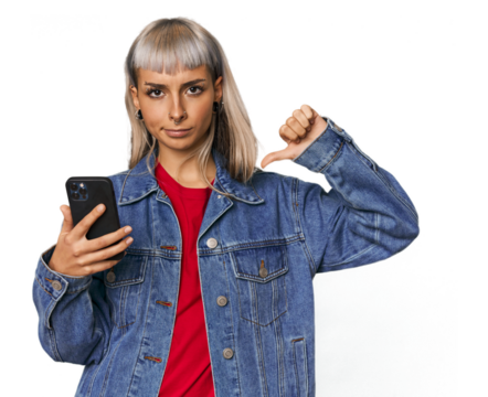 Caucasian young woman with a smartphone showing a dislike gesture, thumbs down. Disagreement concept.