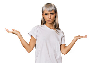 Young caucasian young woman in studio confused and doubtful shrugging shoulders to hold a copy space.