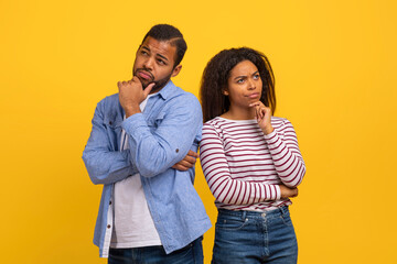 Obraz premium A young African American man and woman stand with their backs to each other, both appearing thoughtful and concerned.