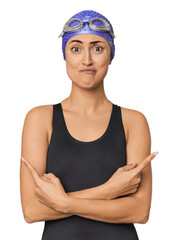 Young Caucasian female professional swimmer points sideways, is trying to choose between two options.