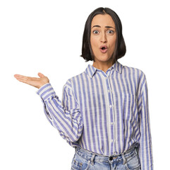 Young Caucasian woman with short hair impressed holding copy space on palm.