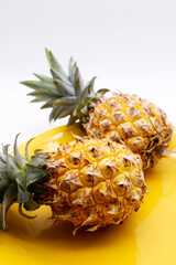 Pineapple fruits placed on yellow plate with white background. Ripe pineapple texture. Fresh fruits...