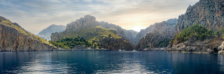 Cala de Sa Calobra bay from the sea, bathed in morning sunlight, framed by Serra de Tramuntana mountains, ideal for promoting tranquil vacations, coastal exploration and nature tourism in Mallorca.