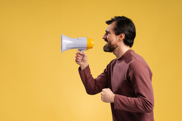 Handsome man with beard shouting through a megaphone, side view, isolated