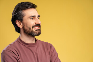 Smiling bearded young man posing in studio looking to the side. Copy space. Advertisement concept