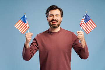 Happy man holding national flags of United States on blue background