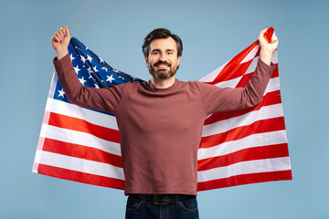 Handsome bearded man with USA flag on blue background in studio