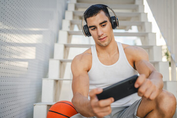 Portrait of man use headphones and smart phone to play video games