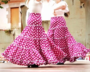 A couple of flamenco dancers in pink polka dots skirts with ruffles and frills performing Sevillanas, a typical Spanish flamenco dance