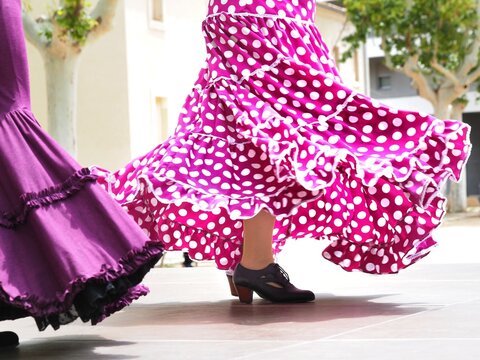 Flamenco dancer in a pink polka dots skirt with ruffles and frills performing Sevillanas, a typical Spanish flamenco dance