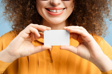 Smiling woman with curly hair businesswoman holding blank business card mockup