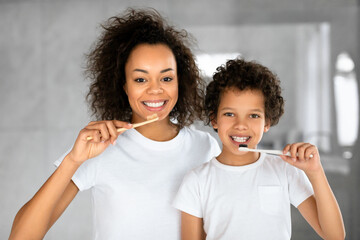 African American mother and her young child, both donning white t-shirts, share a cheerful moment...