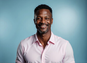 Fototapeta premium Portrait of a middle-aged african american man smiling at the camera on blue background