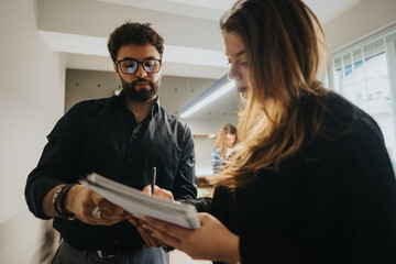 Focused male and female colleagues discussing project details over a notebook in a busy office...