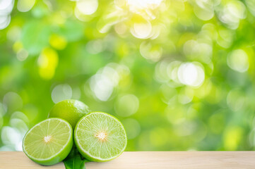 Cut and whole lemons on the wooden floor. Green and blurred background.