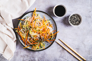 Appetizing salad of funchose, carrots, cucumber and sesame on a plate on the table top view