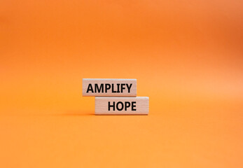 Amplify Hope symbol. Wooden blocks with words Amplify Hope. Beautiful orange background. Business...