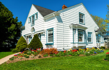 An older style tradional home with flower beds full of springtime flowers.