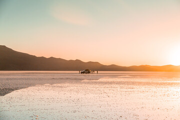 Reflections at Salar de Uyuni during sunset -April- - 4x4 Jeep and tourists behind mountain and mirror lake