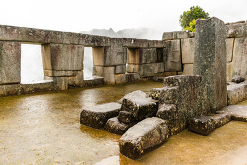 Ancient structures  with three windows in an inca's city at the top of a mountain in a cloudy day in Perú
These ruins are slowly falling and the picture shows an inclined wall