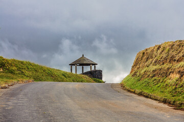 gazebo next to the road to a high hill against the background of a gloomy sky at Sao Miguel island, Portugal