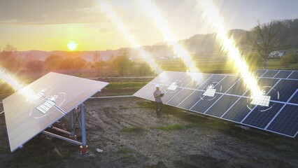 Solar panels farm at sunset, engineer technician working on site with smart tablet device checking...