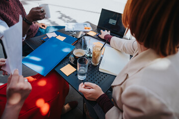 Entrepreneurial team collaborates on project planning over coffee in an informal business meeting setting.