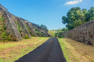 Road in a field between stone walls under a blue sky. Sao Miguel island, Portugal