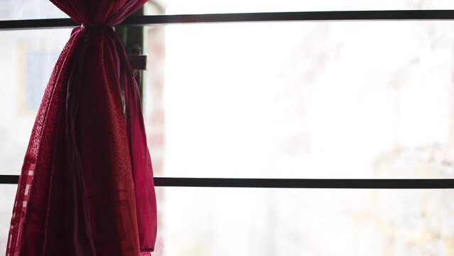 Plano horizontal de una ventana por dentro con una cortina roja 
