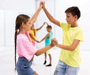 Kids in pairs exercising salsa moves together during group dance class.