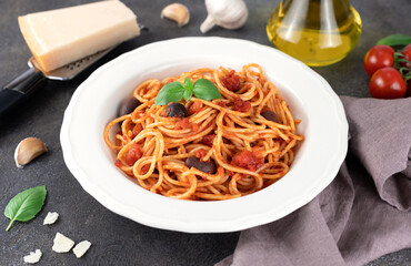 Spaghetti alla puttanesca or Neapolitan pasta on a gray background. Italian Cuisine. 