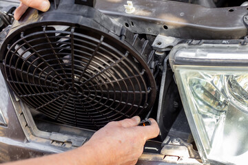 installing a car engine cooling fan under the radiator grille. Car repair and maintenance.