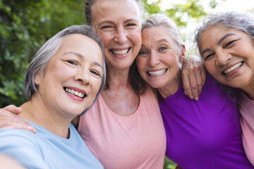 Outdoors, diverse senior female friends smiling together