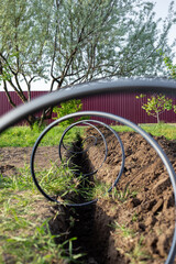 plastic pipe for supplying water to a drip irrigation system, twisted into a spiral, lies on top of a dug ditch. Installation of automatic drip irrigation for the garden.