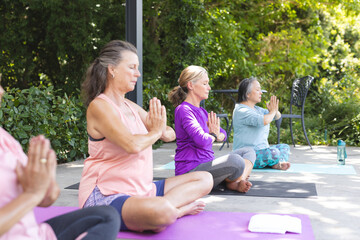 Outdoors, diverse senior female friends practicing yoga, focusing on poses