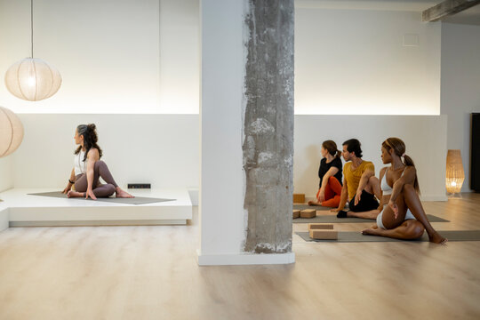 Yoga group twists while seated on mats in a modern studio setting.