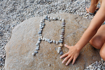 close up view on child hand pointing to letter A made of pebbles