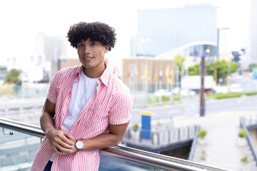 In modern office, biracial young man leaning on railing, looking confident, copy space - Powered by Adobe
