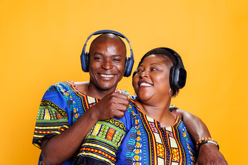 Happy african american romantic couple hugging and enjoying music sound in wireless headphones...