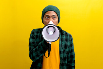 Asian man activist in a beanie hat shouts and yells into a megaphone, demanding change and...