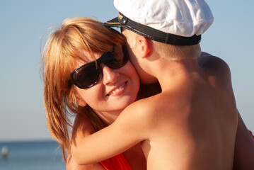 Naklejka premium Little son hugging mother on the seashore