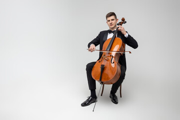 Passionate cello player sitting on chair performing concert © zinkevych