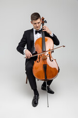 Young male artist sitting on chair and playing contrabass © zinkevych